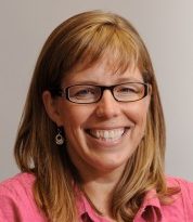 Dr. Michelle Pensec Salyers smiles at the camera while wearing a pink shirt in front of a neutral background